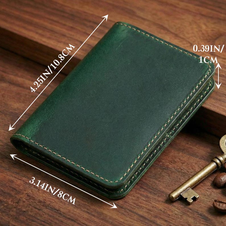 May include: A dark green leather wallet with visible stitching. The wallet measures 4.25 inches by 3.14 inches and is 0.39 inches thick. A vintage key and coffee beans are in the background.