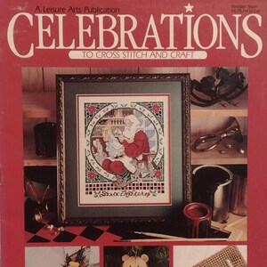 Può includere: Copertina della rivista "Celebrations" con un ricamo a punto croce di Babbo Natale nel suo laboratorio. La copertina presenta progetti natalizi, tra cui una calza, un orsacchiotto e un ricamo "Noël". La rivista è una pubblicazione di Leisure Arts.