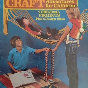 May include: Vintage macrame craft book cover with the title "MACRAME CRAFT Adventures for Children." The cover features a yellow hammock with a doll, and two children holding macrame projects. The background is a blue gradient.