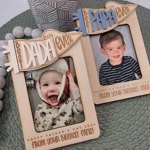 May include: Two wooden photo frames with a banner design. The banners say "Best Dada Ever" and "Best Papa Ever". Each frame has a photo of a child and the text "Happy Father's Day 2024 from your biggest fans!"