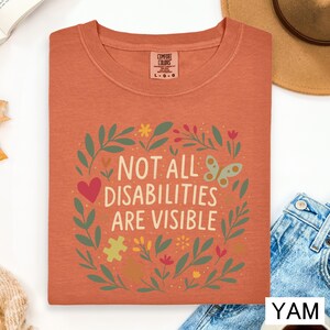 a red t-shirt with a colorful graphic design and text, along with some casual clothing items and a hat.