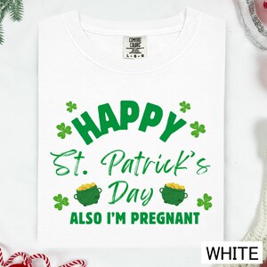 A white t-shirt with a graphic design that says "Happy St. Patrick's Day Also I'm pregnant" in green text.