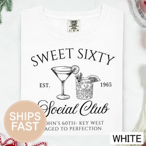 a white t-shirt with a graphic design that includes a cocktail glass and a lemon slice, along with text that reads "Sweet Sixty" and "Social Club".