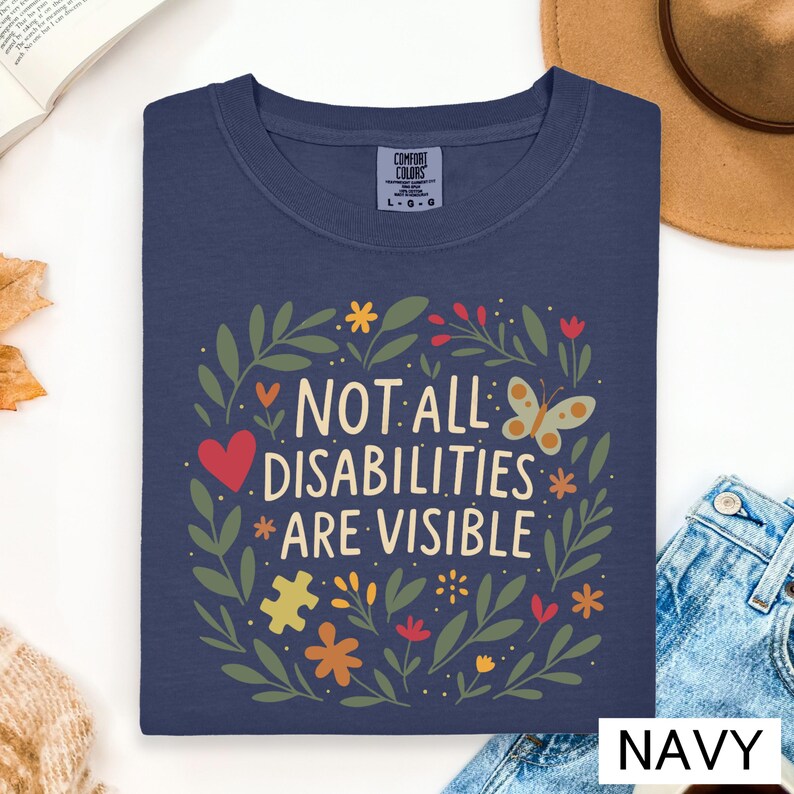 a blue t-shirt with a colorful graphic design and text, along with some other items such as a hat, a book, and a cup.
