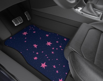 May include: Car floor mat featuring a navy blue backdrop adorned with pink stars of diverse sizes. The mat, with a curved edge and black border, is rectangular. It is positioned within a car's interior.