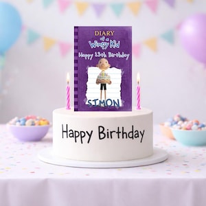 May include: A white birthday cake with the words "Happy Birthday" in black. A purple "Diary of a Wimpy Kid" book is on top, with a cartoon character and the name "Simon". Two pink candles are lit.