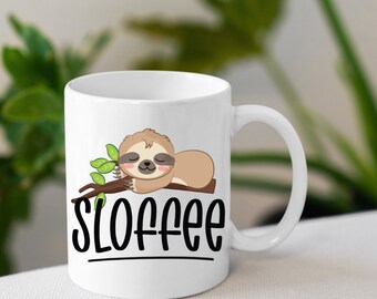 May include: White ceramic mug featuring a cartoon sloth sleeping on a branch. The mug has the text "Sloffee" printed on it in black.