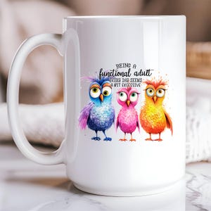 May include: White ceramic coffee mug with a colorful illustration of three owls and the text "Being a functional adult every day seems a bit excessive".