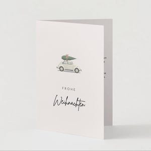 Puede incluir: Tarjeta de felicitación plegada con fondo rosa claro. Presenta un pequeño coche blanco con un árbol de Navidad encima. Las palabras "FROHE Weihnachten" están escritas en fuente cursiva.