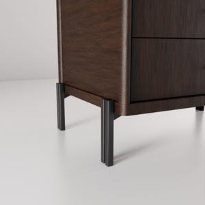 May include: A dark brown wooden cabinet with two drawers and black metal legs. The cabinet has a smooth, polished finish and a modern design. The legs are rectangular and provide a sturdy base.