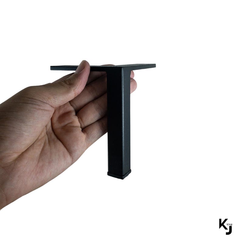 May include: Black metal furniture leg with a square base and a rectangular top plate. The leg is about 6 inches tall.