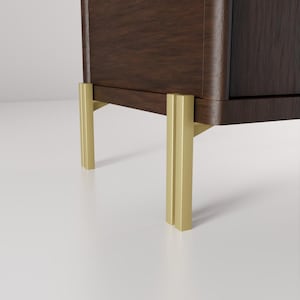 May include: A close-up of a dark brown wooden cabinet with gold-colored metal legs. The cabinet has a curved edge and a smooth finish. The legs are rectangular and provide support.
