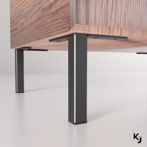 May include: A wooden cabinet with black metal legs. The cabinet has a wood grain finish and a slatted door.