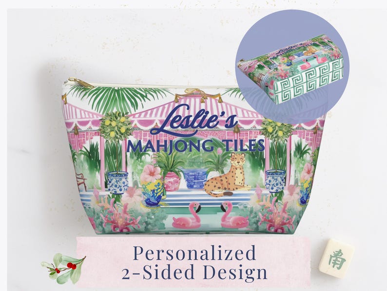 A decorative zip pouch with a pink and green cabana scene and blue Greek key trim. An inset shows the coordinating green Greek key chinoiserie style pattern on the bottom of the bag. Text reads “Leslie’s Mahjong Tiles" to show personalization option.