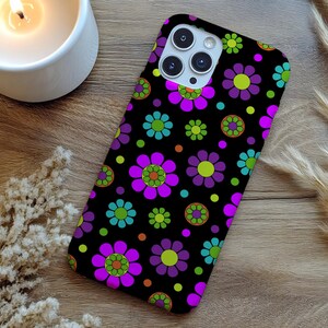 May include: Black phone case with a vibrant floral pattern. The design features large purple flowers with green and orange centers, along with smaller blue and green flowers. The case has a glossy finish.