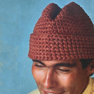 May include: A brown crocheted hat with a pointed top. The hat is made with a simple stitch pattern and has a relaxed fit.