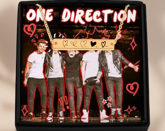 May include: Gold bar necklace featuring the words "ONE DIRECTION" and five hearts. The necklace is presented in a black box with a picture of the band One Direction.