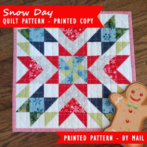 Puede incluir: Un patrón de acolchado impreso para una colcha "Snow Day". El patrón presenta un diseño de estrella con tela roja, blanca, azul, verde y gris. El patrón está impreso en papel blanco e incluye instrucciones para hacer la colcha.
