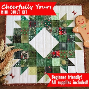 May include: A mini quilt kit with a Christmas theme. The quilt is made of green, red, and white fabric and features a wreath design. The kit includes all the supplies needed to make the quilt. The text on the image reads "Cheerfully Yours. MINI QUILT KIT. Beginner friendly! All supplies included!"