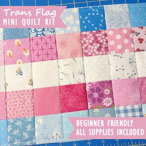 May include: A patchwork mini quilt kit featuring a grid of fabric squares in shades of pink, white, and light blue. The fabric patterns include mushrooms, flowers, polka dots, cats, and scissors. Text reads Trans Flag MINI QUILT KIT and BEGINNER FRIENDLY ALL SUPPLIES INCLUDED.