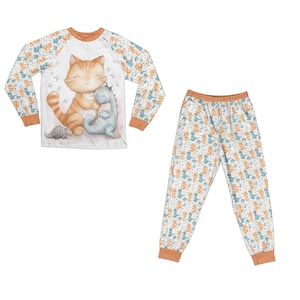 Op de afbeelding: Een wit lang mouw pyjama top met een oranje kat en een blauwe dinosaurus print. De bijpassende pyjama broek heeft een witte achtergrond met een herhalend patroon van oranje katten en blauwe dinosaurussen.