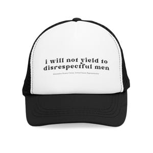 Peut inclure: Casquette de camionneur noire et blanche avec l'inscription "i will not yield to disrespectful men" et le nom "Alexandria Ocasio-Cortez, United States Representative". La casquette a une visière noire et un dos en filet.