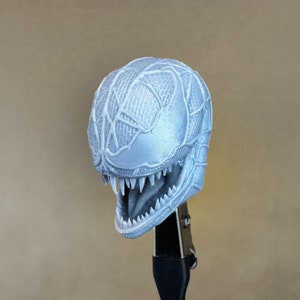Könnte beinhalten: Ein 3D-gedrucktes Modell eines Venom-Kopfes, in hellgrau lackiert. Der Kopf ist mit einem netzartigen Muster verziert und hat einen bedrohlichen, offenen Mund mit scharfen Zähnen.