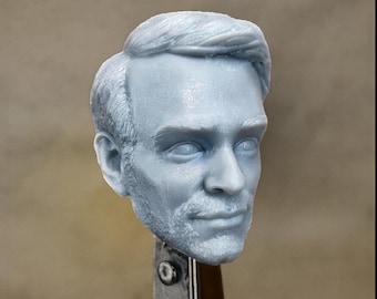 May include: A 3D printed head sculpt of a man with short, styled hair. The head is painted in a light gray color and has a realistic appearance.