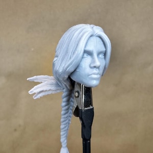 May include: A 3D printed female head with long, braided hair. The hair is styled with a braid and a feather accent. The head is painted in a light grey colour.