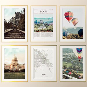 May include: Six framed art prints with gold frames. The prints feature scenic landscapes, including a train track through a mountain tunnel, hot air balloons, a city skyline, a capitol building, and a city map.