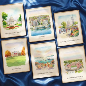 May include: A white ceramic mug with a black handle and the text "But First, Coffee" in a bold, black font. The mug is set against a blurred background, suggesting a cozy setting.