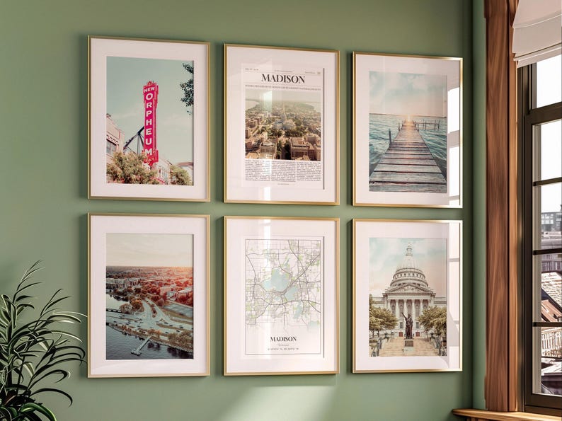 May include: Six framed art prints with gold frames hang on a green wall. The prints feature images of Madison, Wisconsin, including a theater sign, cityscapes, a map, and a pier.