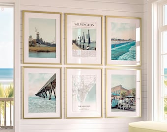 Può includere: Sei stampe artistiche incorniciate con cornici dorate sono esposte su un muro bianco. Le stampe presentano immagini di Wilmington, nella Carolina del Nord, tra cui una corazzata, una scena sulla spiaggia, un molo, una mappa e una carrozza trainata da cavalli. La parola "Wilmington" è visibile su due stampe.