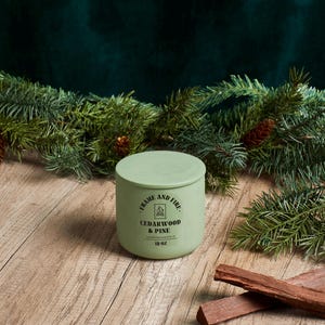 Frame and Fire luxury candles in ceramic jars with lids, featuring scents like Rosewood Lux, Saffron Noir, Cedarwood & Pine, Evergreen Fir, and Woodlands. Hand-poured coconut apricot wax candles styled with holiday decor, perfect for gifting or home