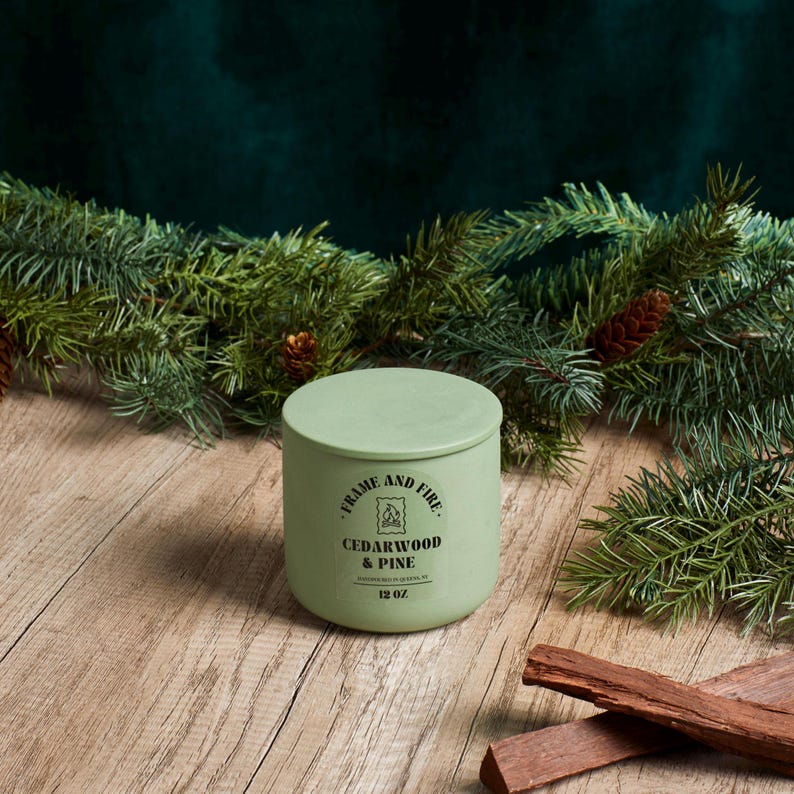 Frame and Fire luxury candles in ceramic jars with lids, featuring scents like Rosewood Lux, Saffron Noir, Cedarwood & Pine, Evergreen Fir, and Woodlands. Hand-poured coconut apricot wax candles styled with holiday decor, perfect for gifting or home
