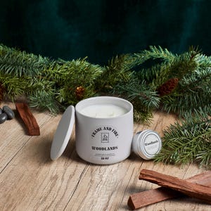Frame and Fire luxury candles in ceramic jars with lids, featuring scents like Rosewood Lux, Saffron Noir, Cedarwood & Pine, Evergreen Fir, and Woodlands. Hand-poured coconut apricot wax candles styled with holiday decor, perfect for gifting or home