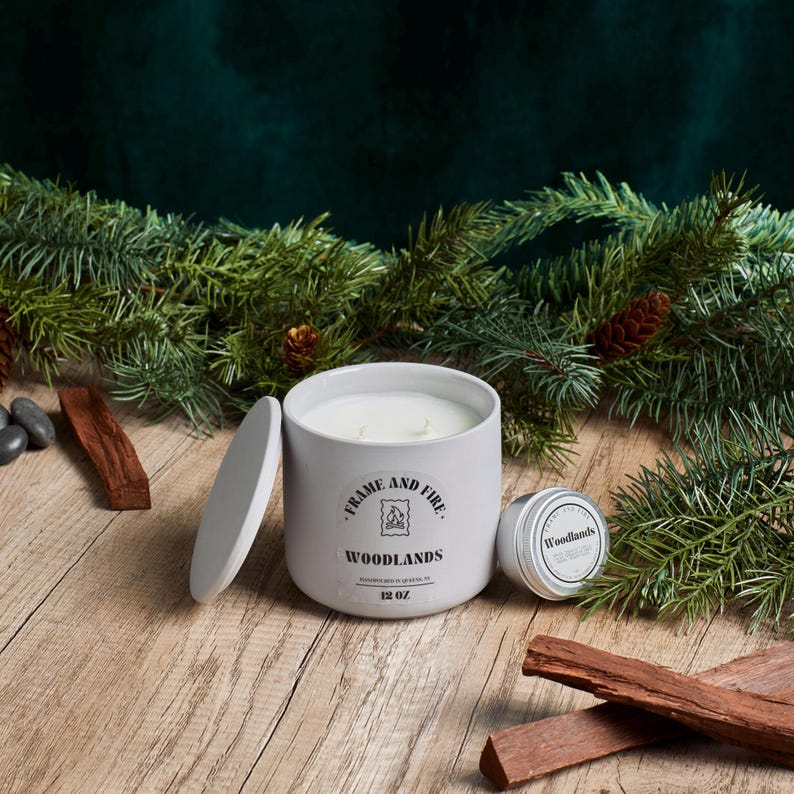 Frame and Fire luxury candles in ceramic jars with lids, featuring scents like Rosewood Lux, Saffron Noir, Cedarwood & Pine, Evergreen Fir, and Woodlands. Hand-poured coconut apricot wax candles styled with holiday decor, perfect for gifting or home
