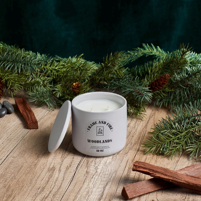 Frame and Fire luxury candles in ceramic jars with lids, featuring scents like Rosewood Lux, Saffron Noir, Cedarwood & Pine, Evergreen Fir, and Woodlands. Hand-poured coconut apricot wax candles styled with holiday decor, perfect for gifting or home