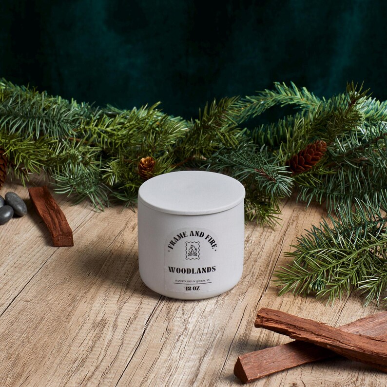 Frame and Fire luxury candles in ceramic jars with lids, featuring scents like Rosewood Lux, Saffron Noir, Cedarwood & Pine, Evergreen Fir, and Woodlands. Hand-poured coconut apricot wax candles styled with holiday decor, perfect for gifting or home
