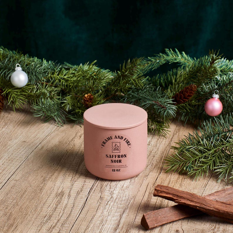 Frame and Fire luxury candles in ceramic jars with lids, featuring scents like Rosewood Lux, Saffron Noir, Cedarwood & Pine, Evergreen Fir, and Woodlands. Hand-poured coconut apricot wax candles styled with holiday decor, perfect for gifting or home