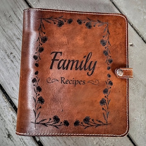 May include: A brown leather recipe binder with a floral design and the text "Family Recipes" engraved on the front.