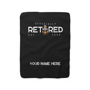 Pode incluir: Cobertor de lã preto com texto branco que diz "Oficialmente Reformado" com uma âncora dourada e as letras "USN" no meio. O texto "Est" e "Ano" estão de cada lado da âncora. O texto "Seu Nome Aqui" está na parte inferior do cobertor.