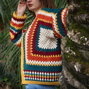 May include: A colorful crochet cardigan with a multi-colored geometric pattern in shades of red, orange, yellow, green, and white.