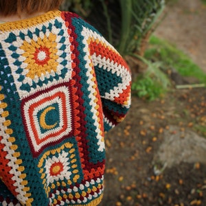May include: A crocheted cardigan with a colorful geometric pattern in shades of teal, orange, red, and white.