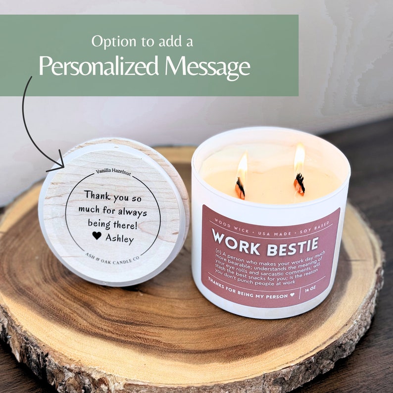 May include: A white candle with a wooden wick and a soy base. The candle is labelled "Work Bestie" and has a pink heart with the text "Thanks for being my person". The candle is on a wooden surface with a lid that says "Thank you so much for always being there! Ashley".