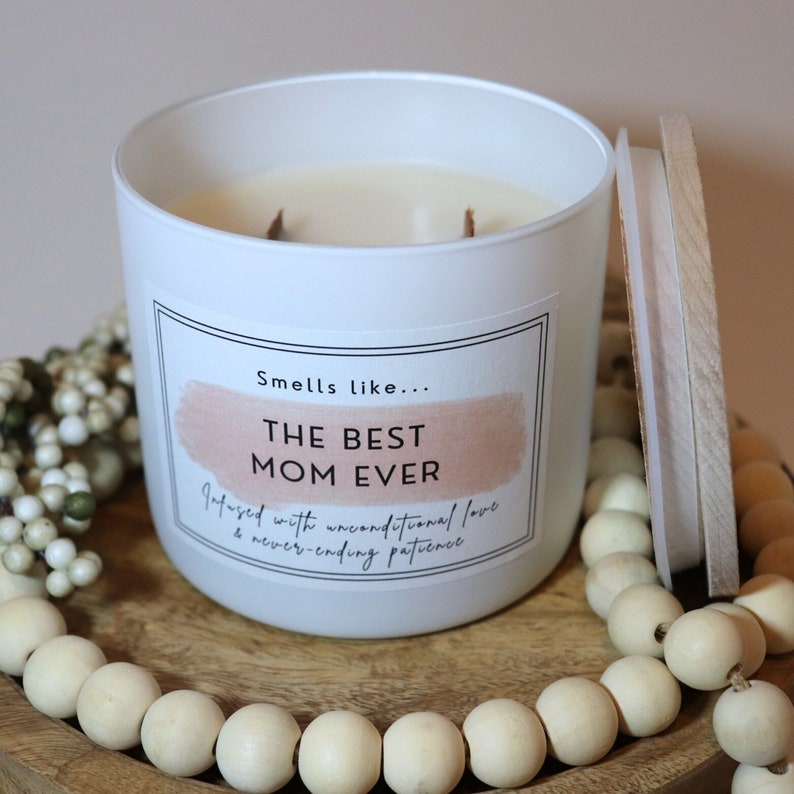 May include: White candle jar with a pink and white label that reads "Smells like... THE BEST MOM EVER Infused with unconditional love & never-ending patience".