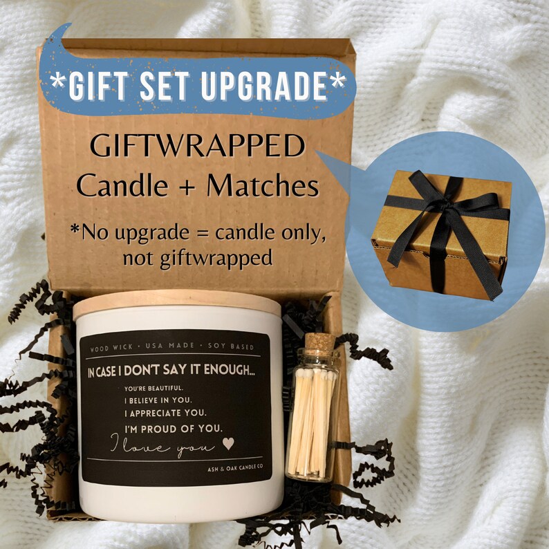 May include: A gift set containing a white candle with a black label that reads "In case I don't say it enough... You're beautiful. I believe in you. I appreciate you. I'm proud of you. I love you." and a small glass jar filled with matches. The candle and matches are in a brown box with black shredded paper. The box is wrapped in brown paper with a black ribbon.