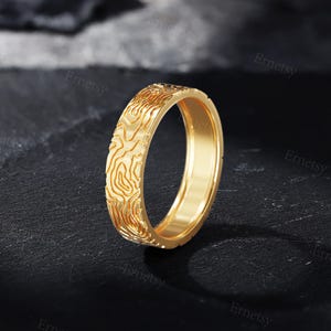 a gold wedding band with a carved design