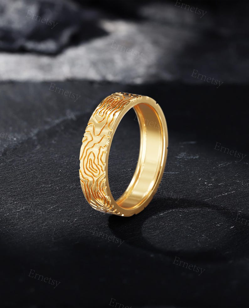 a gold wedding band with a carved design
