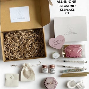 K&ouml;nnte beinhalten: Ein DIY-Muttermilch-Andenken-Kit mit verschiedenen Komponenten, die auf einer wei&szlig;en Oberfl&auml;che angeordnet sind. Das Kit enth&auml;lt Harz, Spritzen, eine Ringbox, einen kleinen Beutel mit einem Herz und eine herzf&ouml;rmige rosa Karte mit der Aufschrift "Thanks, Gorgeous!". Das Kit ist mit "ALL-IN-ONE BREASTMILK KEEPSAKE KIT" beschriftet.